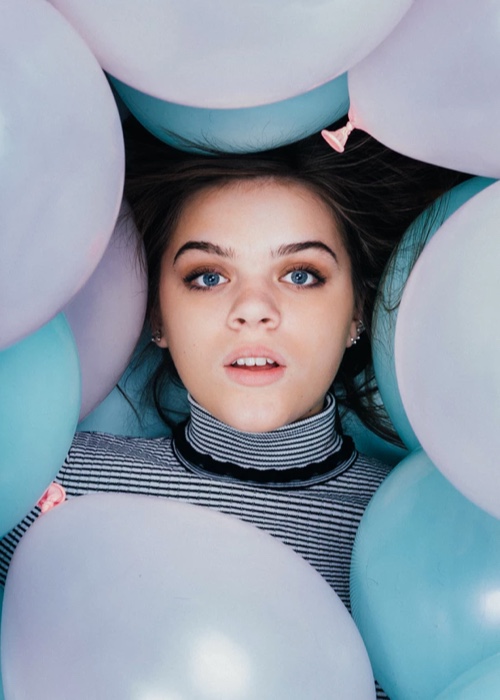 Harper is surrounded by a bunch of skyblue and light pink balloons.